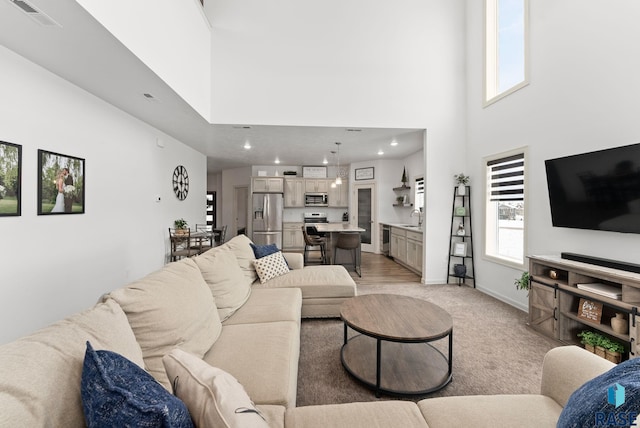 living room featuring light colored carpet, sink, a towering ceiling, and wine cooler