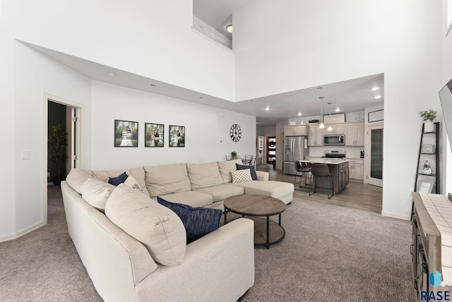 living room with a towering ceiling and light colored carpet