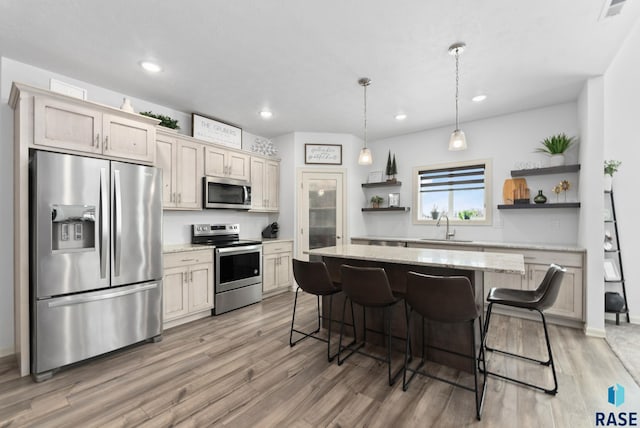 kitchen with a kitchen island, sink, light stone counters, appliances with stainless steel finishes, and pendant lighting