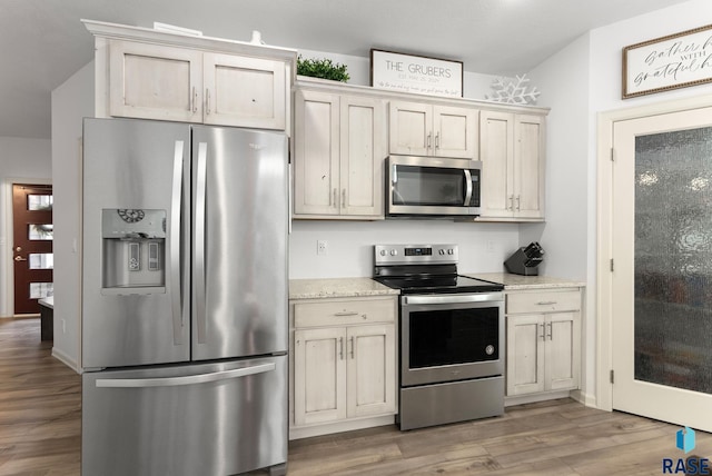 kitchen featuring appliances with stainless steel finishes, light stone counters, and hardwood / wood-style flooring