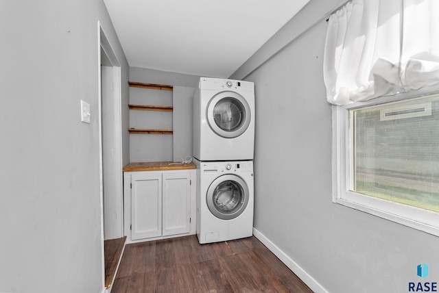 laundry room with cabinets, dark hardwood / wood-style flooring, and stacked washer and clothes dryer