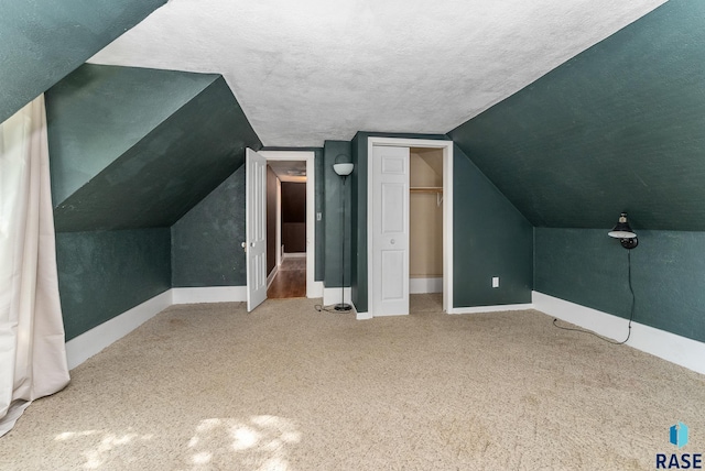 bonus room featuring a textured ceiling, lofted ceiling, and carpet