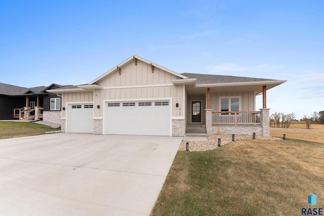 view of front of property featuring covered porch, a front yard, and a garage