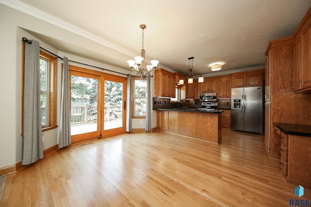 kitchen with stainless steel appliances, ornamental molding, an inviting chandelier, hanging light fixtures, and light hardwood / wood-style flooring