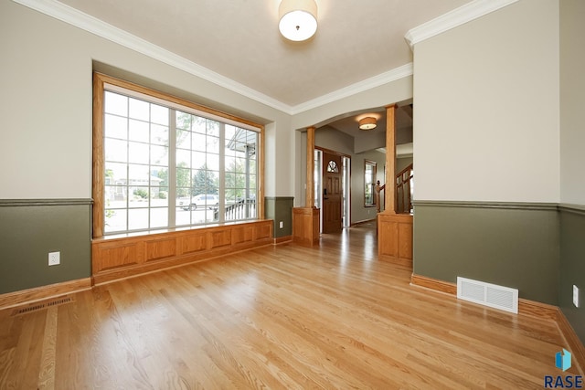 spare room with crown molding, ornate columns, and light hardwood / wood-style floors