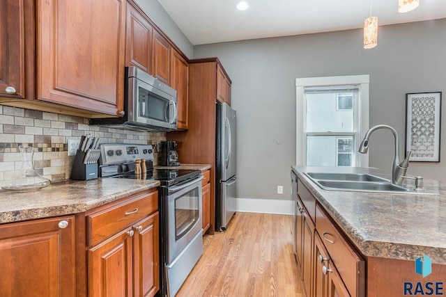 kitchen featuring brown cabinets, dark countertops, a sink, and appliances with stainless steel finishes