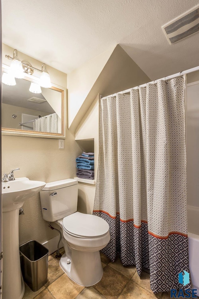 full bath featuring toilet, visible vents, a sink, and a textured ceiling