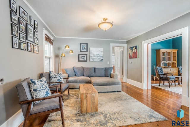 living area with baseboards, wood finished floors, and ornamental molding