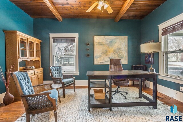 office area featuring a ceiling fan, light wood finished floors, baseboards, wooden ceiling, and beam ceiling