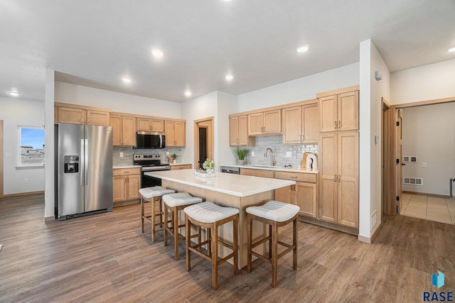 kitchen with a breakfast bar, a kitchen island, visible vents, light countertops, and appliances with stainless steel finishes