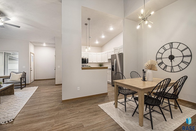 dining room with dark wood finished floors, recessed lighting, a towering ceiling, baseboards, and ceiling fan with notable chandelier