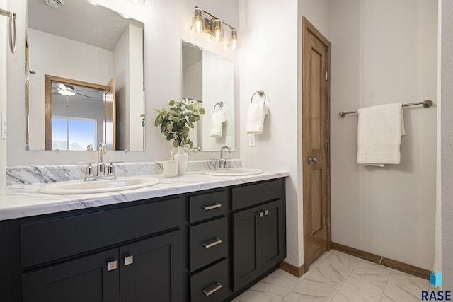 full bathroom with marble finish floor, double vanity, a sink, and baseboards