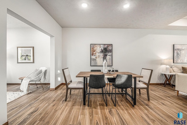 dining space featuring a textured ceiling, baseboards, and wood finished floors