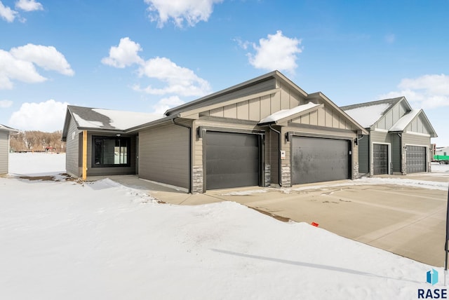 view of front of house featuring an attached garage, stone siding, and board and batten siding