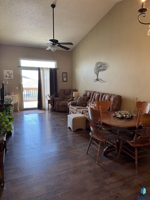 dining area with dark wood-style floors, a ceiling fan, vaulted ceiling, and a textured ceiling