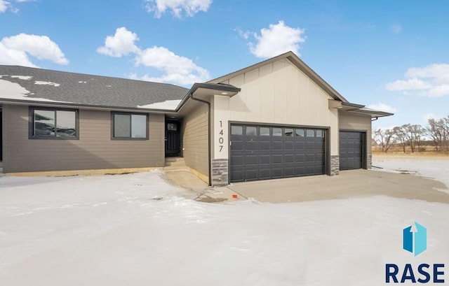 view of front of home featuring a garage, stone siding, and board and batten siding