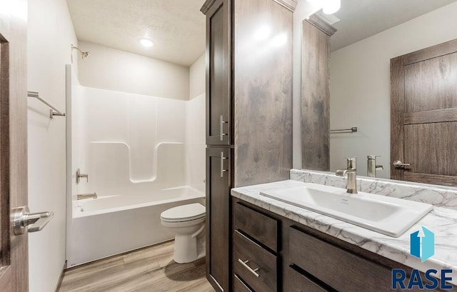 full bath with shower / bathtub combination, a textured ceiling, toilet, wood finished floors, and vanity