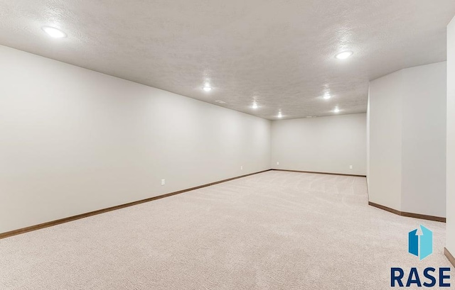 finished below grade area with light carpet, baseboards, a textured ceiling, and recessed lighting