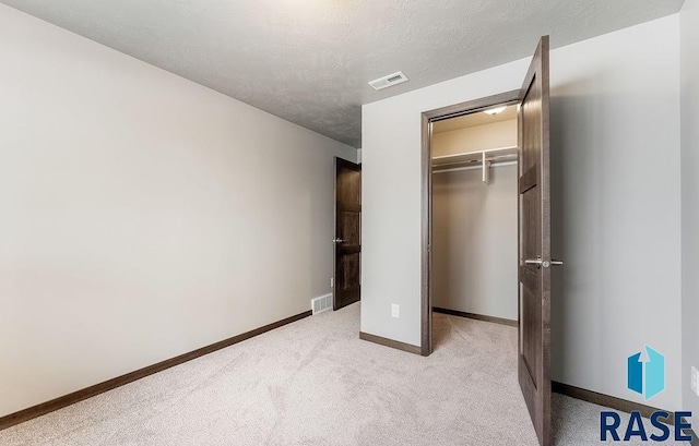 unfurnished bedroom featuring a closet, visible vents, a textured ceiling, and baseboards