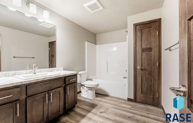 bathroom featuring visible vents, toilet, a textured ceiling, vanity, and wood finished floors