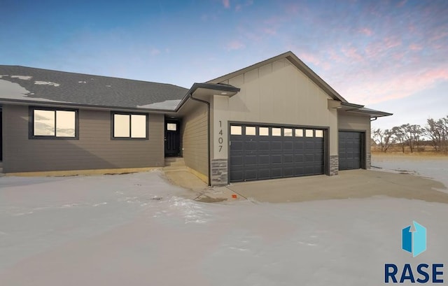 view of front of property featuring a garage, stone siding, and board and batten siding