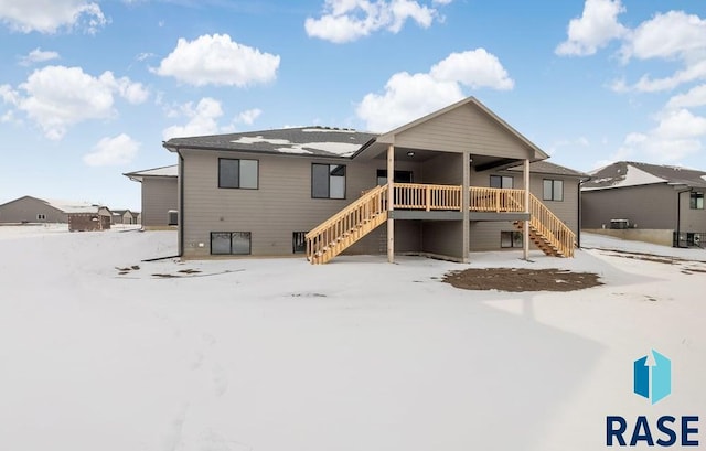 snow covered rear of property with stairway and a deck