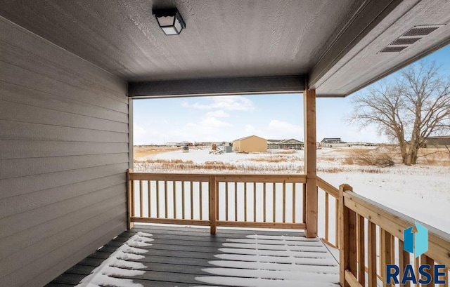 snow covered deck featuring visible vents