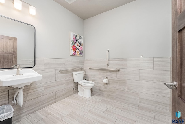 bathroom featuring toilet, a wainscoted wall, a sink, and tile walls