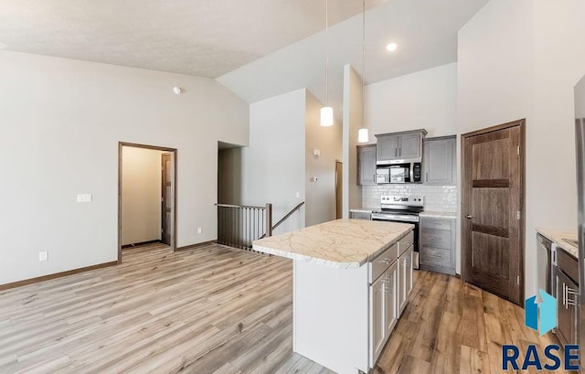 kitchen with appliances with stainless steel finishes, a center island, light countertops, and gray cabinetry