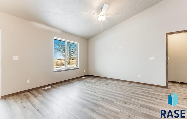 spare room featuring light wood-style floors, ceiling fan, baseboards, and vaulted ceiling