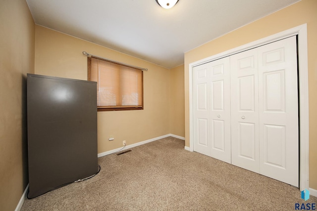 unfurnished bedroom featuring a closet, carpet flooring, visible vents, and baseboards