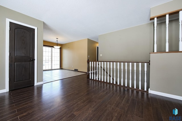 unfurnished room with dark wood-type flooring and baseboards