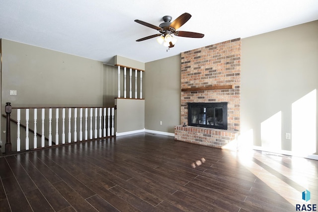 unfurnished living room featuring a ceiling fan, dark wood-style flooring, a fireplace, and baseboards