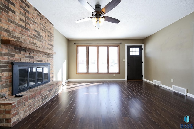 unfurnished living room featuring dark wood-style floors, a brick fireplace, and visible vents