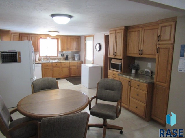 kitchen featuring brown cabinetry, white appliances, and a sink