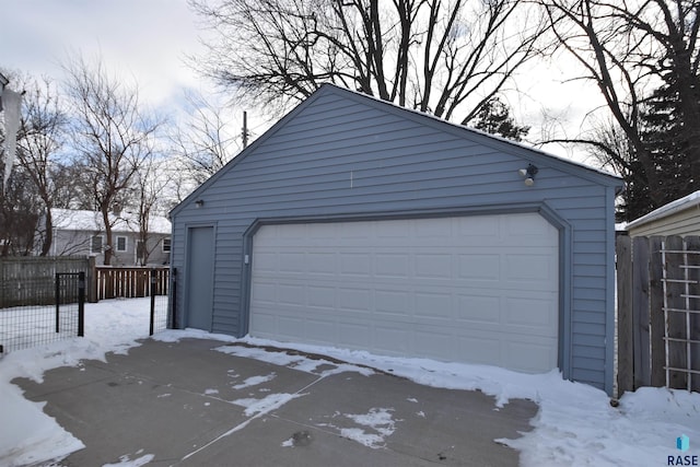 snow covered garage with a garage and fence