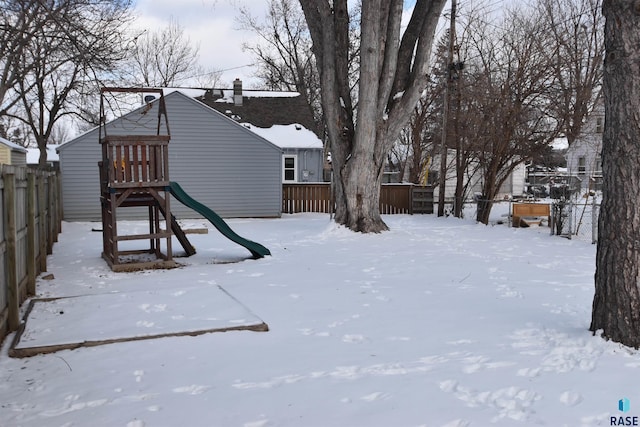 snowy yard with a playground and fence