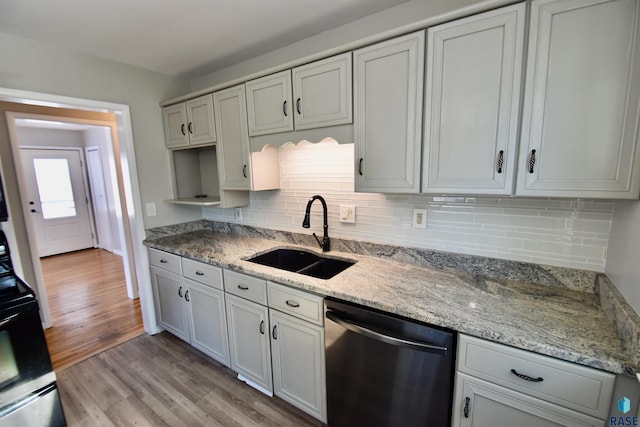 kitchen with light stone counters, white cabinets, a sink, light wood-type flooring, and dishwasher