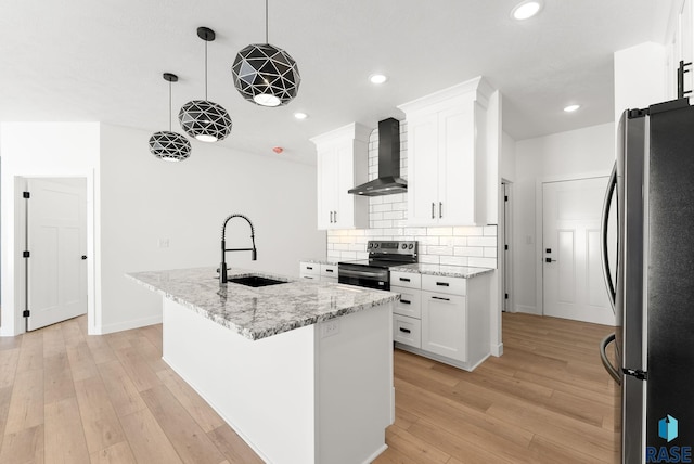 kitchen featuring a center island with sink, stainless steel appliances, white cabinetry, a sink, and wall chimney exhaust hood