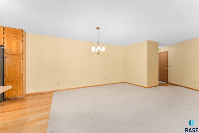 unfurnished room with baseboards, a chandelier, and a textured ceiling