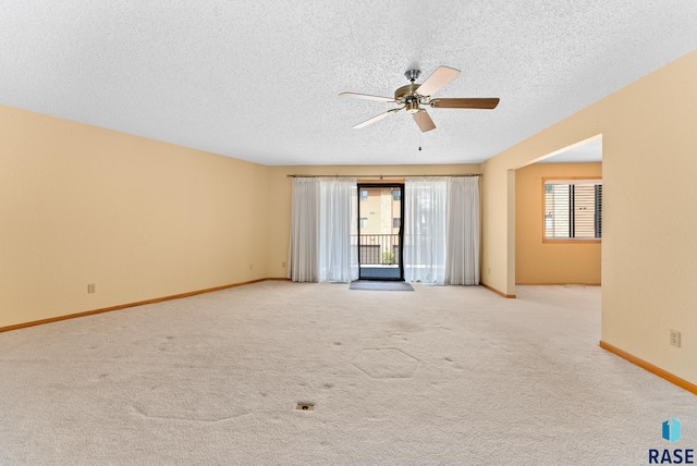 empty room featuring light carpet, baseboards, and a textured ceiling