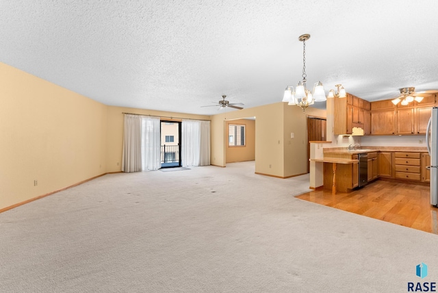 kitchen featuring light countertops, hanging light fixtures, freestanding refrigerator, open floor plan, and dishwashing machine