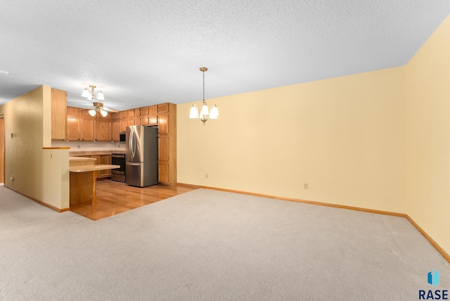 kitchen featuring light colored carpet, open floor plan, stainless steel appliances, light countertops, and pendant lighting