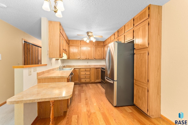 kitchen with light wood finished floors, light countertops, appliances with stainless steel finishes, and a kitchen breakfast bar