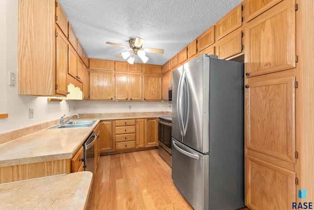 kitchen with a sink, stainless steel appliances, light countertops, and light wood-style flooring