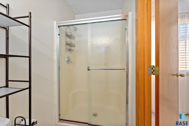 full bath with a shower with door and a textured ceiling