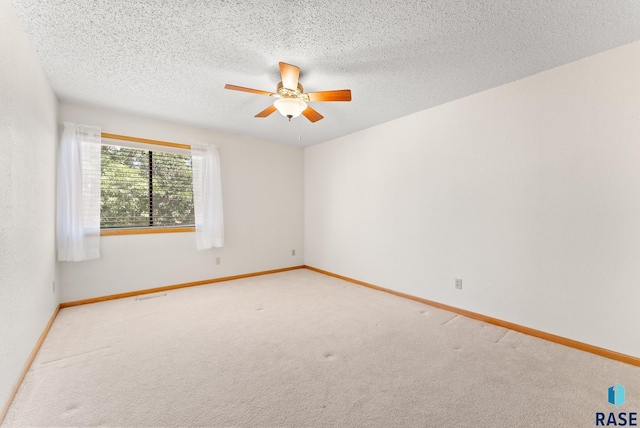 spare room with baseboards, ceiling fan, a textured ceiling, and light colored carpet