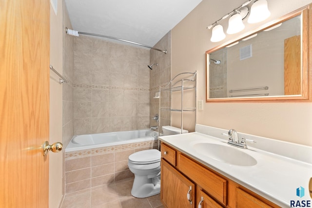 bathroom featuring tiled shower / bath, visible vents, toilet, vanity, and tile patterned flooring