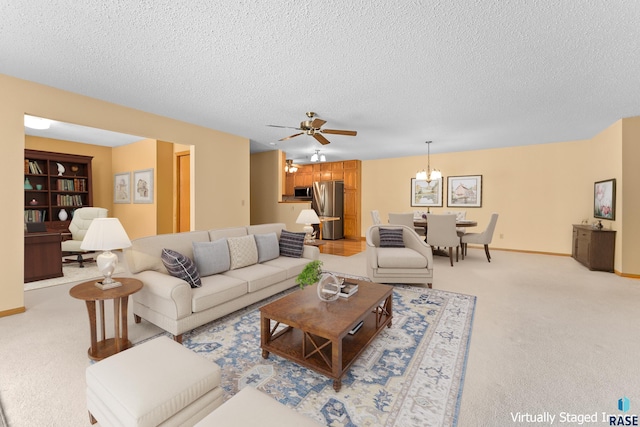 living area with baseboards, ceiling fan with notable chandelier, a textured ceiling, and light colored carpet