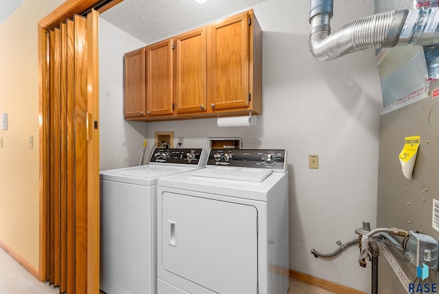 laundry room featuring baseboards, cabinet space, washer and clothes dryer, and a textured ceiling